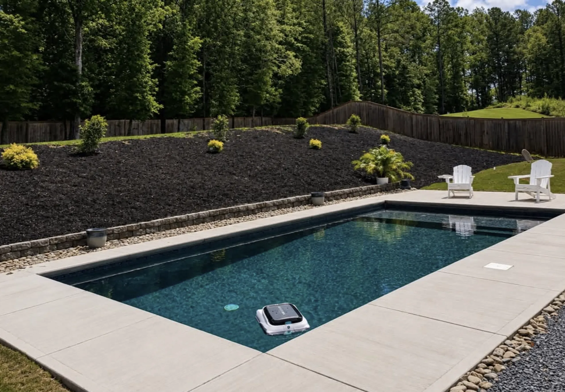 Dark-bottom rectangular pool set into a landscaped, mulched slope